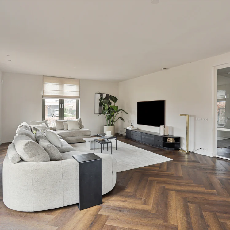 Woonkamer met een rustige uitstraling dankzij de Hebeta Cayenne Visgraat XL - Eiken rustiek goud bruin - 15,3 cm x 76,5 cm vloer in bruin eiken.